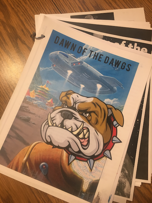 Printed pages, bound with a ring; top page includes a landing spaceship and a bulldog mascot.