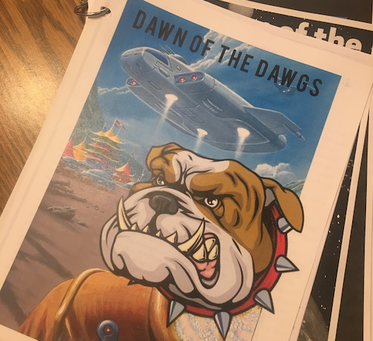 Printed pages, bound with a ring; top page includes a landing spaceship and a bulldog mascot.