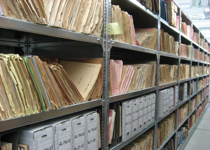 A photo of shelves of paper files in an archive.