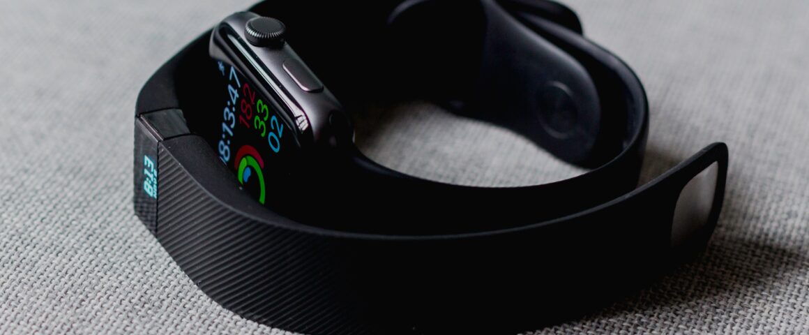 A black, wearable Fitbit lies on a table, displaying a user's health information.