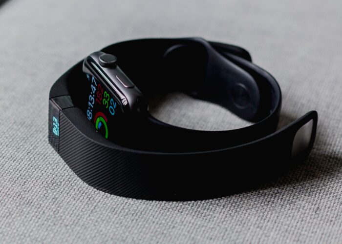 A black, wearable Fitbit lies on a table, displaying a user's health information.
