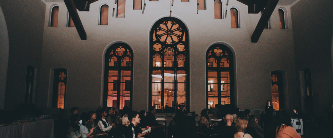Conference attendees are pictured from the side, under dramatic Russian Orthodox church windows.